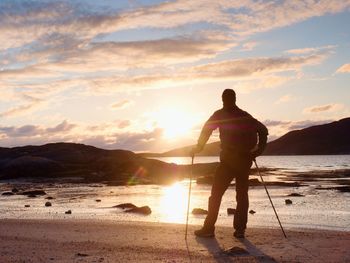 Walker watch sunny  daybreak over sea. sun rays mirrored in water and wet sand. hiking ambition.