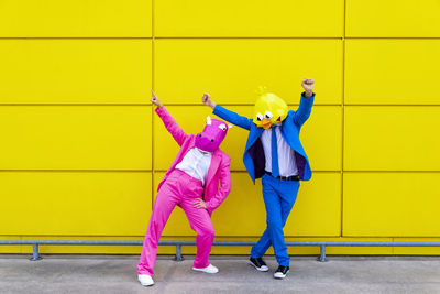 Full length of woman standing against yellow wall