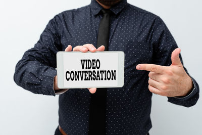 Midsection of man holding mobile phone against white background