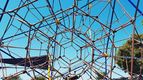 Low angle view of jungle gym against clear blue sky