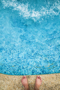 Low section of woman standing on swimming pool