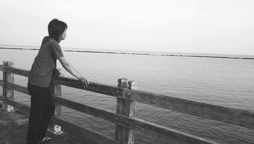 Man looking at see while standing by railing