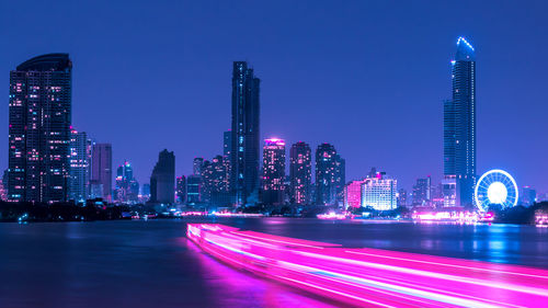 Light trails on illuminated buildings in city at night