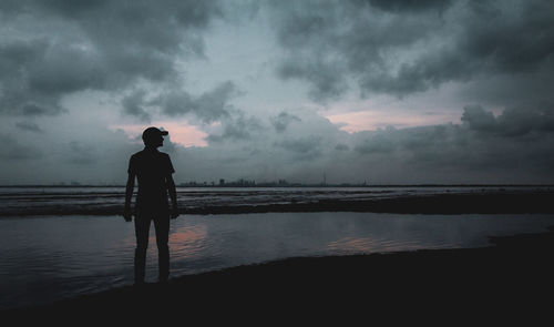 Silhouette man standing at beach against sky