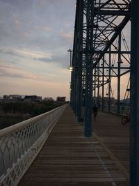 Footbridge against sky at sunset