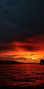 Scenic view of sea against dramatic sky during sunset