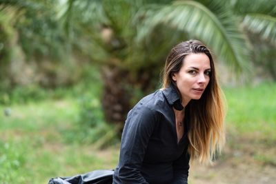 Portrait of beautiful young woman against plants