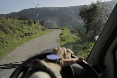 Close-up of man driving car on road against sky