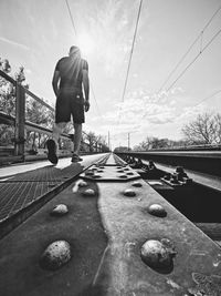 Rear view of man on shore against sky
