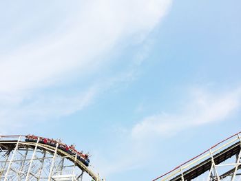 People on rollercoaster against sky