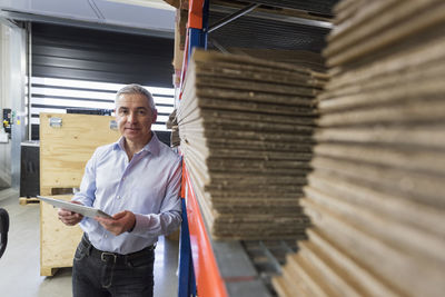 Portrait of businessman with tablet in factory hall