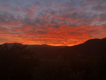 Scenic view of silhouette mountains against dramatic sky