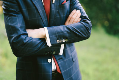 Midsection of man holding umbrella standing on field