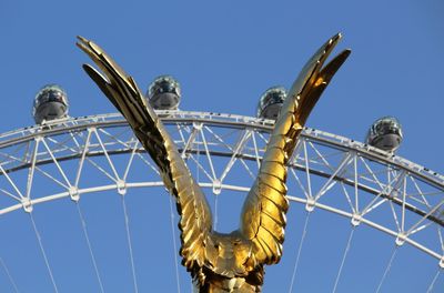 Low angle view of rollercoaster against clear blue sky