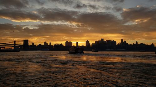 Silhouette buildings in city against sky during sunset