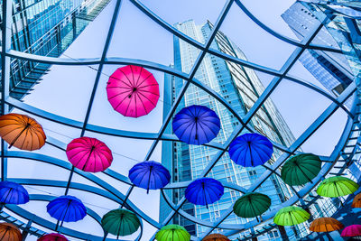 Low angle view of modern buildings and colorful umbrella decorations in city