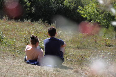 Rear view of friends sitting on field