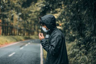 Side view of man wearing mask standing on road