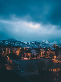 Illuminated buildings in town against sky at night
