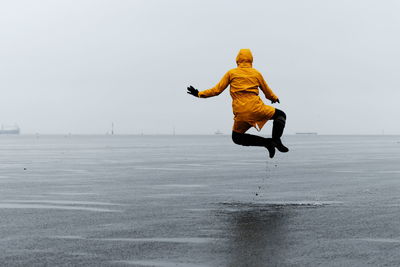 Full length of man jumping on beach against sky