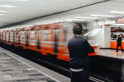 Rear view of man standing at subway station