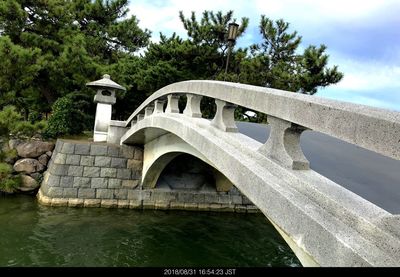 Arch bridge over river against sky