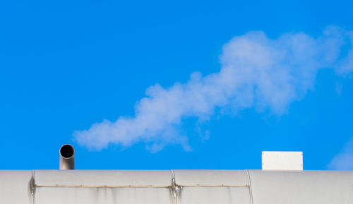 Low angle view of smoke stacks against blue sky