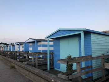 Houses on beach by buildings against clear blue sky