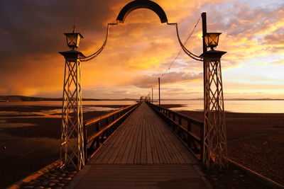 View of footbridge against cloudy sky at sunset