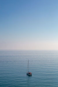 Scenic view of sea and yacht against clear sky