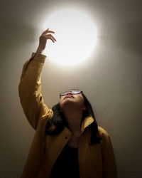 Woman gesturing against sun standing outdoors