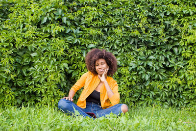 Portrait of a smiling young woman sitting on plants