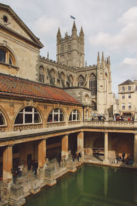 Cropped built structure against clouds with pond in foreground