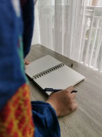 Midsection of person reading book on table