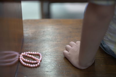 Midsection of girl sitting by necklace on table