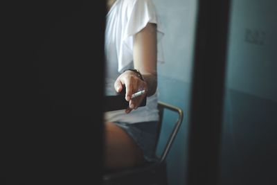 Midsection of woman smoking while sitting on chair