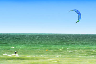 Person kiteboarding on board against clear sky