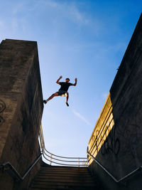 Low angle view of man jumping against sky
