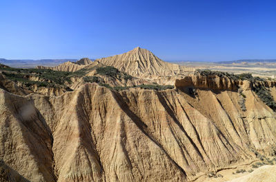 Panoramic view of arid landscape against clear blue sky