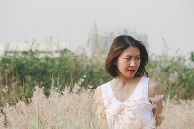 Young woman looking away while standing outdoors