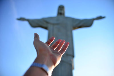 Low angle view of human hand against christ the redeemer