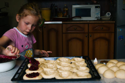 A girl prepares pies with lingonberries in the kitchen