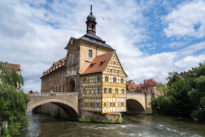 Arch bridge over river amidst buildings against sky