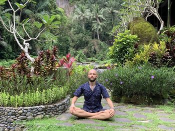 Portrait of young man sitting on field, yoga and meditation 