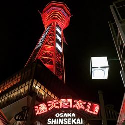 Low angle view of illuminated sign against sky at night