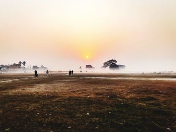 People on field against sky during sunset