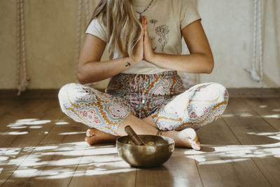 Low section of woman sitting on hardwood floor doing meditation