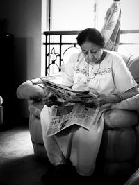 Young woman sitting on book at home