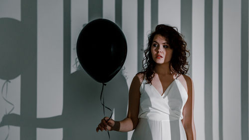 Portrait of smiling young woman standing against wall