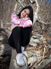 Portrait of woman sitting on fallen tree